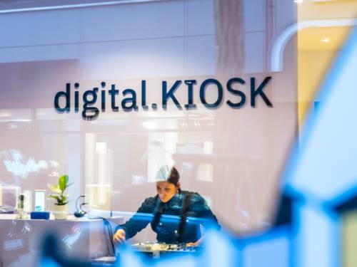 Eine Person an einem Mischpult – fotografiert durch eine Scheibe.