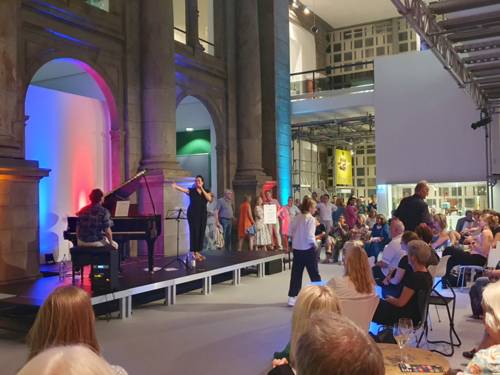 Eine S&auml;ngerin und ein Pianist stehen vor Publikum auf einer B&uuml;hne im Museum August Kestner
