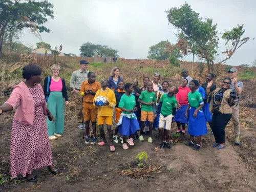 Das Projektteam, Schüler*innen und Lehrkräfte der Namiwawa Primary School mit einem Setzling.