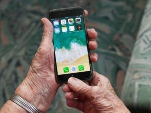 Hände einer älteren Person, die ein Handy benutzen