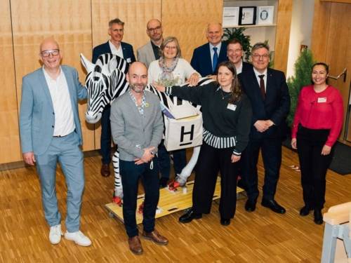 Menschen neben einem lebensgroßen Modell eines Zebras.