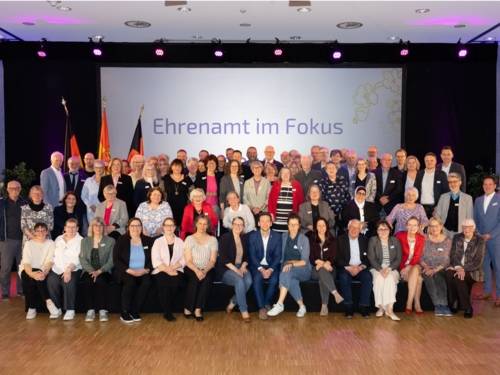 Ein Gruppenfoto mit den Geehrten Personen im Rahmen der Veranstaltung. Auf der Leinwand im Hintergrund steht "Ehrenamt im Fokus".