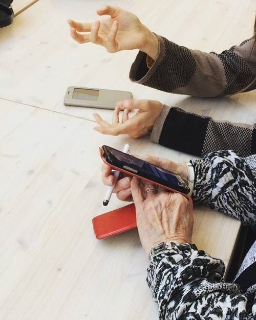 Zwei Hände, einmal von einer älteren Person und einmal von einer jüngeren Person, arbeiten gemeinsam an einem Mobiltelefon.