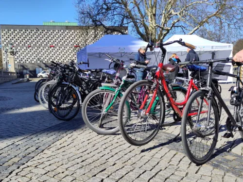 Zahlreiche Fahrräder stehen auf einem Platz, dahinter steht ein weißes Zelt.