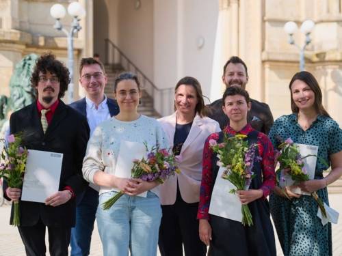 Menschen mit Urkunden und Blumensträußen