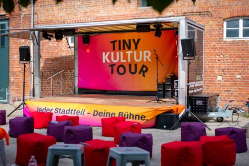 Eine Wort-Bild-Marke in der "TINY KULTUR TOUR" steht.