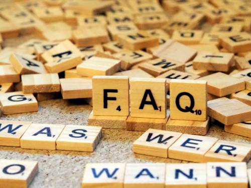Holzbuchstaben liegen durcheinander, erkennbar sind Frageworte und auf hochkant stehenden Holzplättchen: "FAQ"