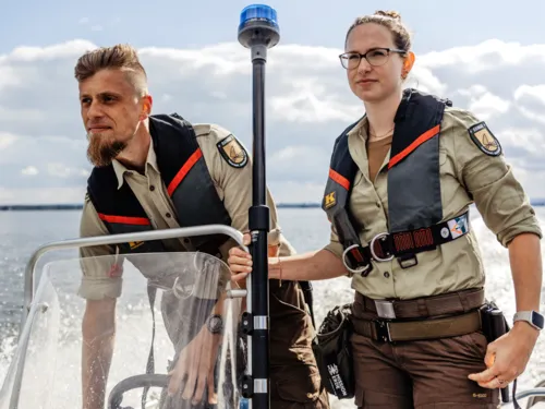 Eine Rangerin und ein Ranger fahren mit einem Boot.
