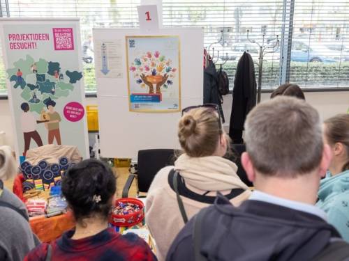 Menschen betrachten einen Infostand