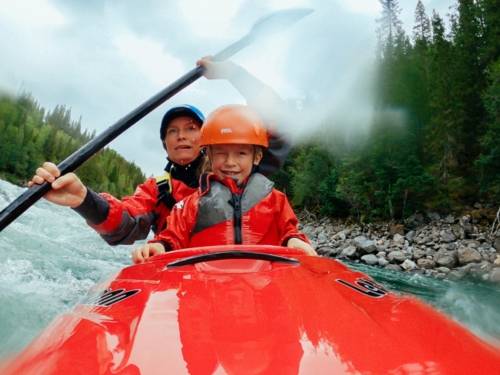 Zu sehen ist eine Frau und ein Kind in einem roten Kayak auf dem Wasser