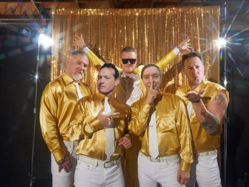 Fünf Männer in weißen Hosen, goldenen Hemden und weißen Krawatten.