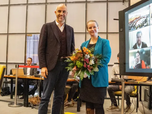Zwei Personen mit einem Blumenstrauss in einem Saal.