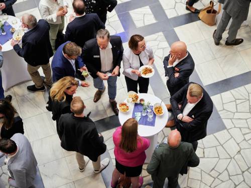 Menschen an einem Stehtisch von oben fotografiert.