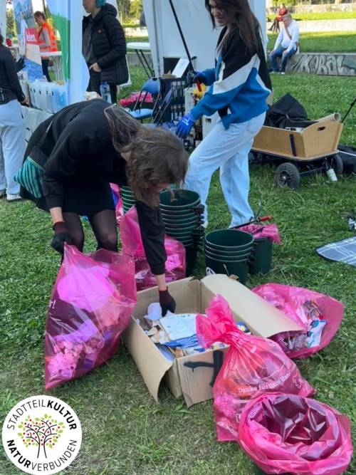 Frau in orangem Anzug zieht einen Mülleimer hinter sich auf einer Straße.