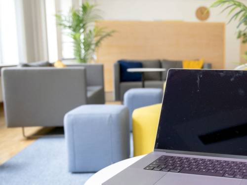 Hinter einem Laptop ist eine bunte Sitzlandschaft.