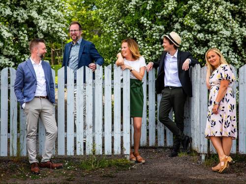 Die zwei Sängerinnen und drei Sänger des Ensembles stehen an einem Gartenzaun.