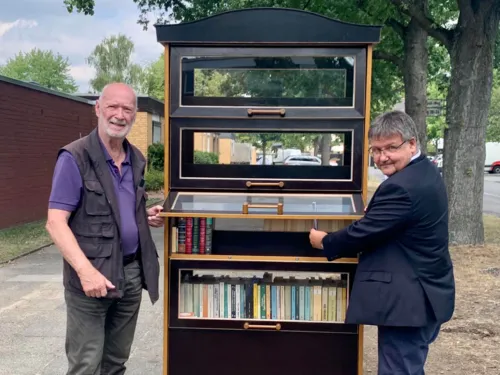 Zwei Personen an einem Schrank voller Bücher.