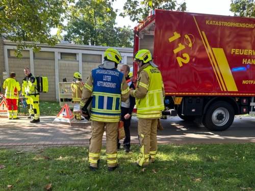 Zwei Einsatzleiter*innen stehen vor einem mobilen Behandlungsplatz und dem Gerätwagen Notfallrettung