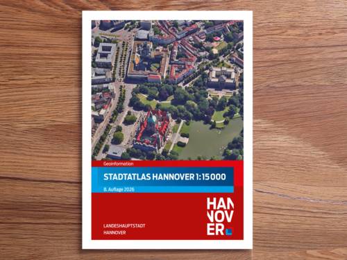 Eine Seite mit einem Luftbild von einem Stadtausschnitt und dem Titel Stadtatlas Hannover 1:15 000 auf einem Holzfurnier