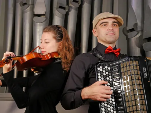 Eine Musikerin spielt auf einer Geige und ein Mann auf einem Akkordeon