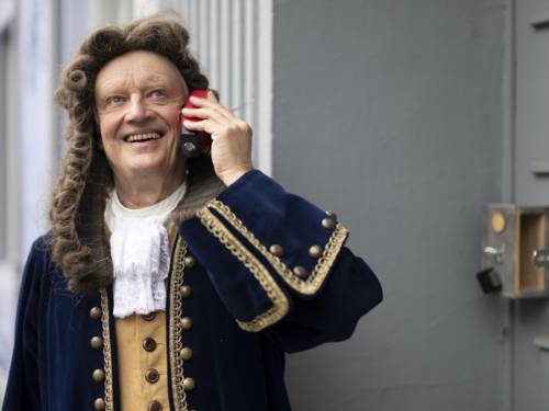 Ein Schauspieler in Verkleidung hält ein Handy an sein Ohr.