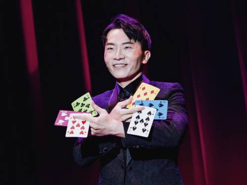 Illusionist hält je drei Spielkarten in seinen Händen.