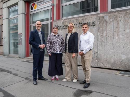 Eine Gruppe aus zwei Frauen und zwei Männern steht vor einem Haus.