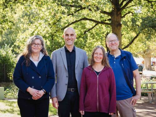 Vier Personen auf einem begrünten Platz.