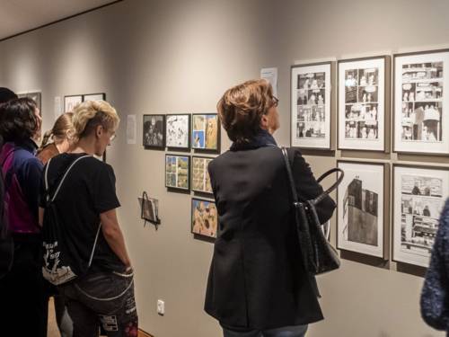 Besuchende schauen auf an Wänden aufgehängte Karikaturen und Comicseiten.