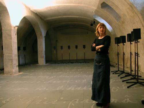 Frau in einem Kammergewölbe umgeben von Lautsprechern.