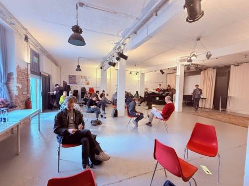 Die Workshopteilnehmer:innen sitzen auf Stühlen im Raum verteilt und schreiben für sich.