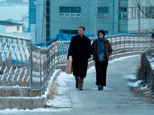 Ein Mann und eine Frau gehen über eine Brücke. Es liegt ein wenig Schnee