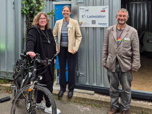 Drei Personen vor einer Ladestation.