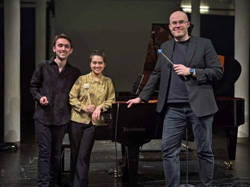 Zwei Männer und eine Frau an einen Konzertflügel gelehnt.