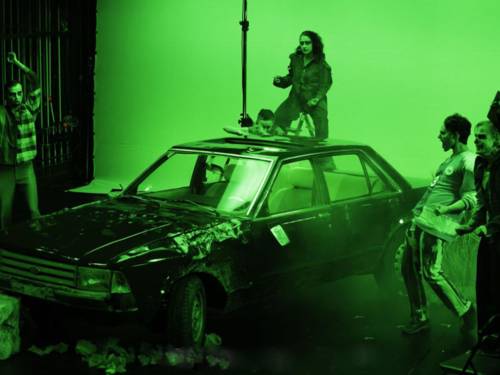 Vier Schauspieler stehen auf einer Bühne um ein Auto herum.