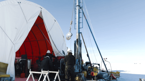 Wissenschaftler mit Sedimentbohrer in Eislandschaft.