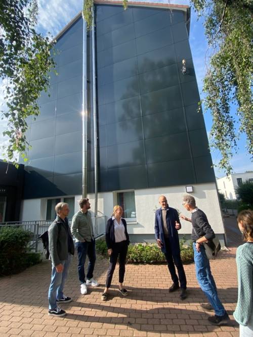 Ein Teil der Gruppe der PfK steht vor einer Fassadensolaranlage