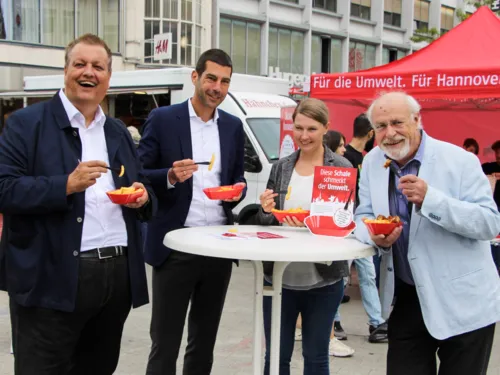 3 M&auml;nner und eine Frau essen Pommes aus Mehrweggeschirr