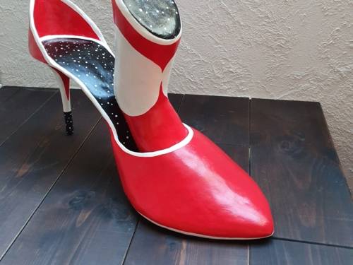 Zu sehen ist eine kleinformatige Skulptur von Tina Wahren eines roten Pumps und einer weiteren Figuration, die im Schuhpositioniert ist.
