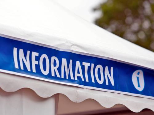 Am Dach eines weißen Zeltes ist ein Banner angebracht. Darauf steht "Information", daneben ist das "i" für Information.