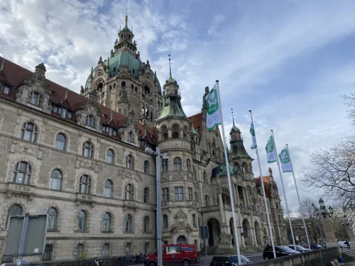 Zu sehen ist das Neue Rathaus. Im Vordergrund wehen 4 Flaggen, die den Frieden in Europa symbolisieren sollen.