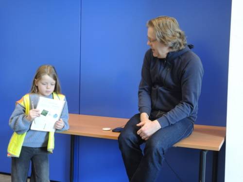 Ein Kind und ein Erwachsener unterhalten sich vor einer blauen Wand.