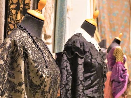 Schaufensterpuppen mit historischen Kleidern aus Spitze und Brokat in einer Ausstellung.