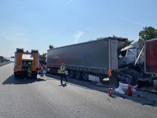 Zwei Lastwagen, die ineinander gefahren sind, stehen neben einem Rettungswagen.
