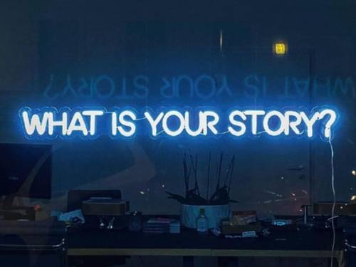 Eine Leuchtreklame, in der steht "What is your story?".