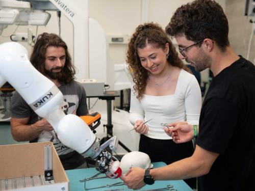 Zwei Männer und eine Frau mit Roboterarm.