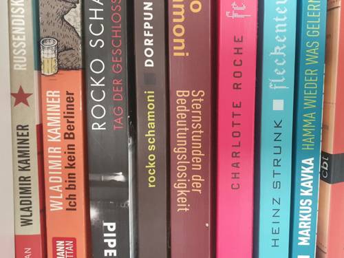 Neun verschiedenfarbige Buchrücken in einem Regal