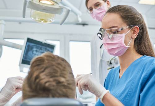 Eine Zahnmedizin-Studentin untersucht den Zahnstand eines Patienten