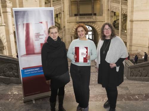 Drei Frauen in einer Halle. Daneben steht ein Schild, auf dem "Stadt-Hannover-Preis" steht.