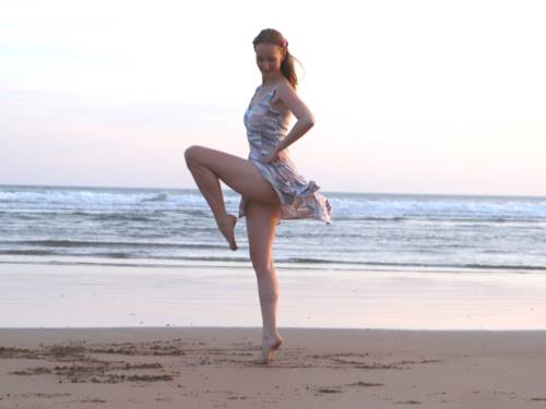 Eine Tänzerin tanzt auf Zehenspitzen am Strand.